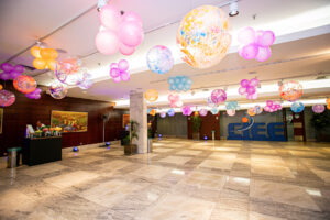 Mostra o espaço do foyer decorado com balões rosas e amarelos