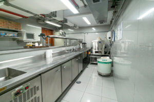 Cozinha industrial, com cores claras, grande pia e espaço para equipe