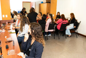 Diversas mulheres sentadas uma ao lado da outra em um camarim