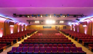 Vista do palco para o teatro, mostra as cadeiras vermelhas de frente