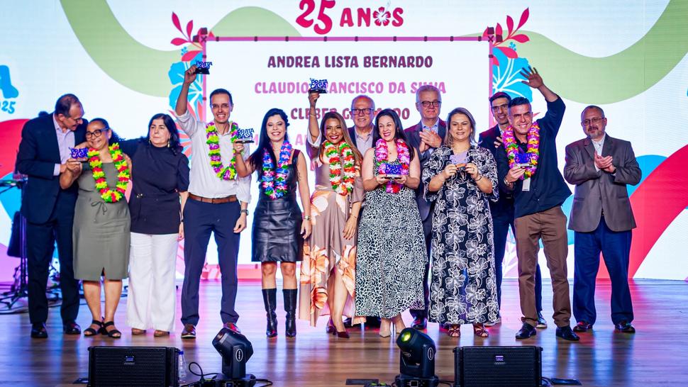 Diversas pessoas vestidas em clima Aloha em cima do palco segurando o Prêmio