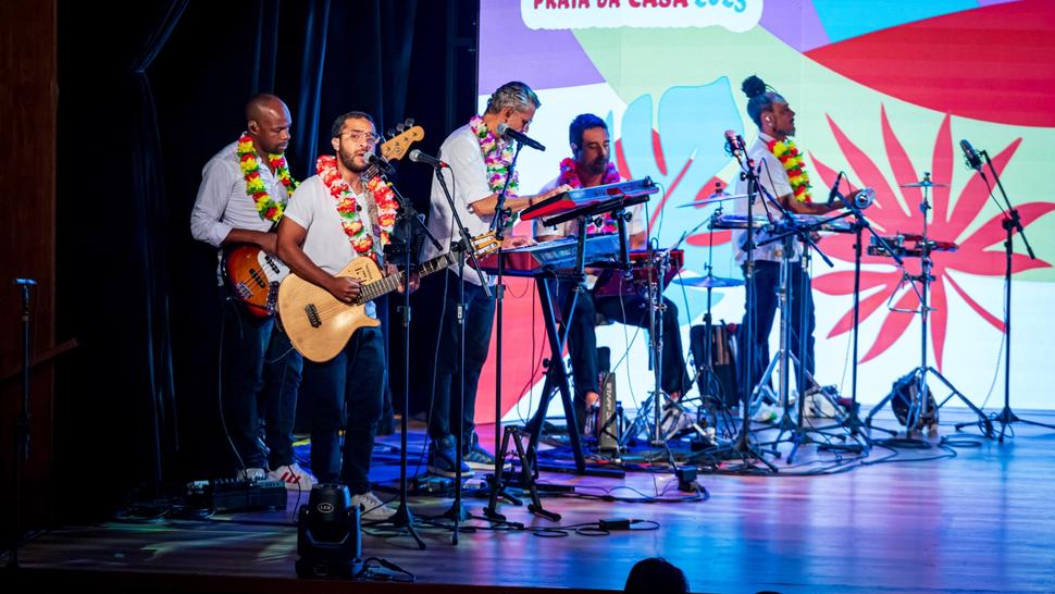 Banca tocando no palco com roupas estilo tropicais.