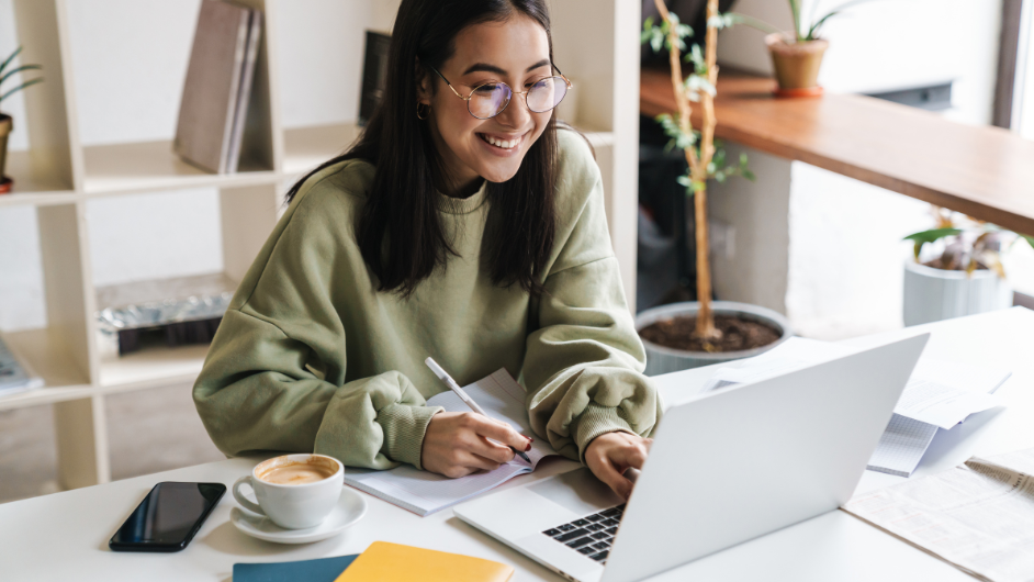 a imagem mostra uma mulher de óculos sorrindo e olhando para o computador, melhorando o currículo